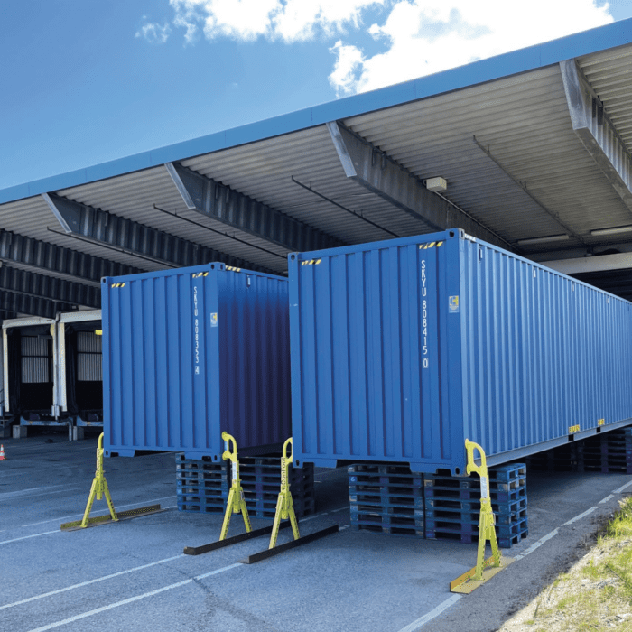 Blå storlagercontainrar 40 fot mot kaj på terminal med containerben