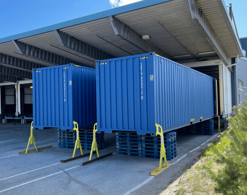 Blå storlagercontainrar 40 fot mot kaj på terminal med containerben