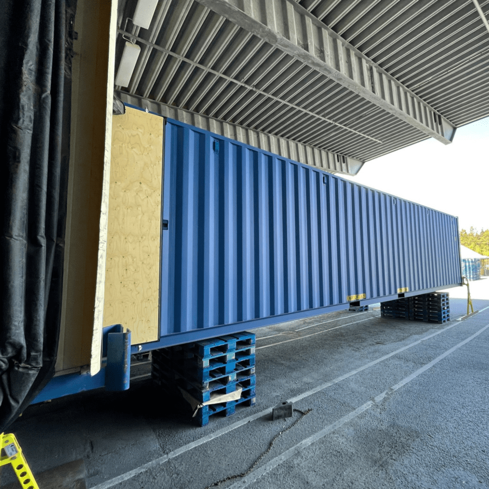 Blå storlagercontainrar 40 fot mot kaj på terminal med containerben